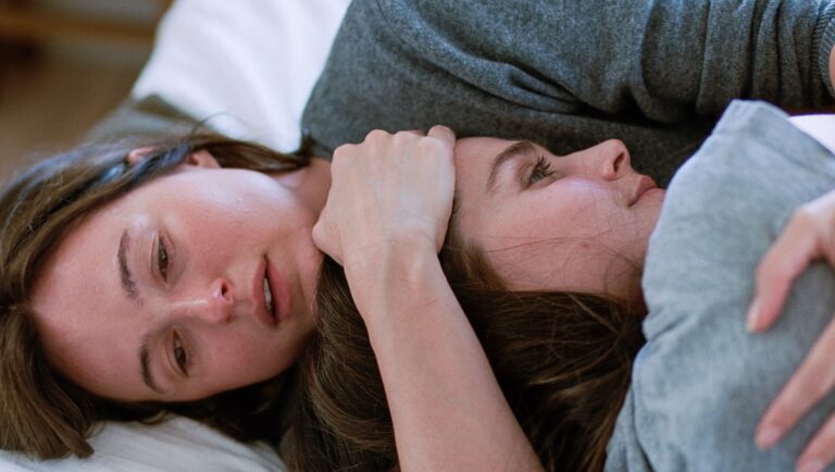 Affectionate lesbian couple cuddling in bed. Two women embracing, showing love and intimacy. LGBTQ+ relationship.