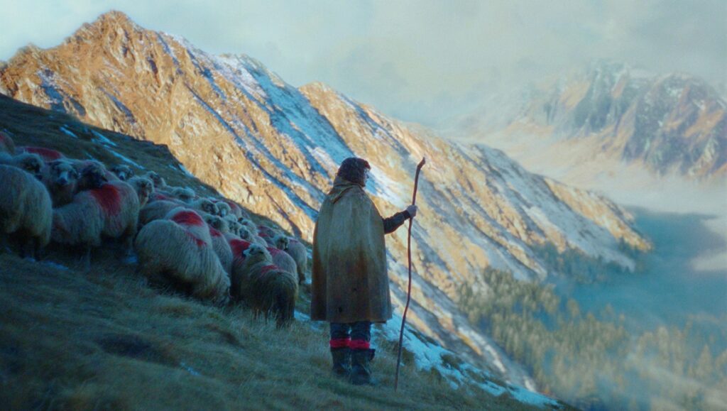 Ochi movie review. Shepherd with sheep flock in mountains. A24 film, April 2025 reviews.