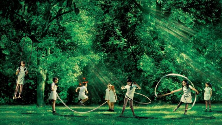 Innocence film still: Girls play in a green forest with swing, jump rope, and hula hoop. Sunlight filters through trees.