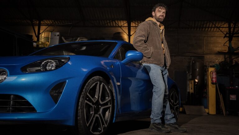 William Dupuy from Last Bullet Netflix, posing with a blue Alpine sports car.