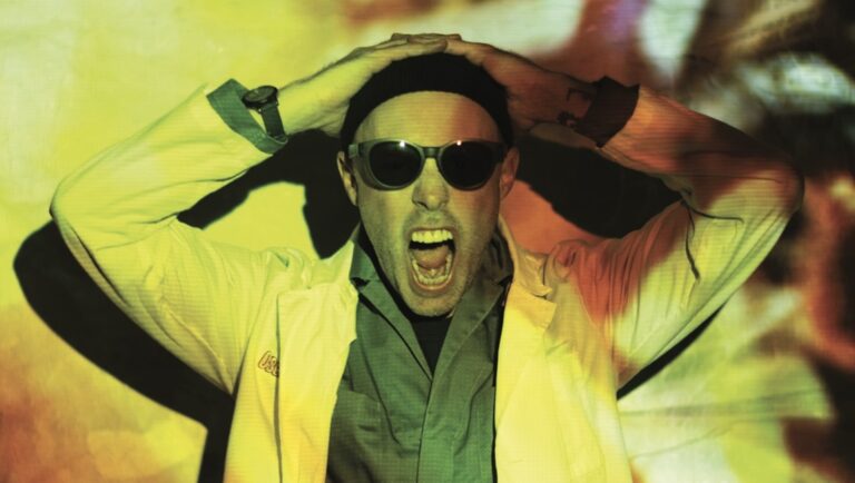 Joel Potrykus interview. Man with sunglasses, hands on head, mouth open. Indie filmmaker portrait.