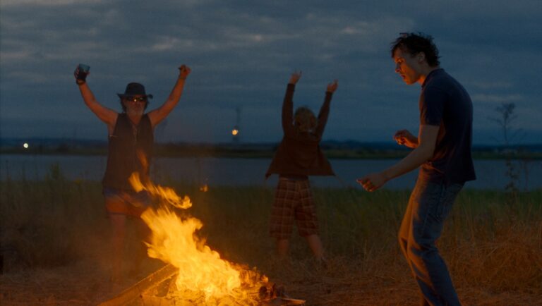 Urchin film scene at Cannes Film Festival: People dance around a bonfire at dusk.