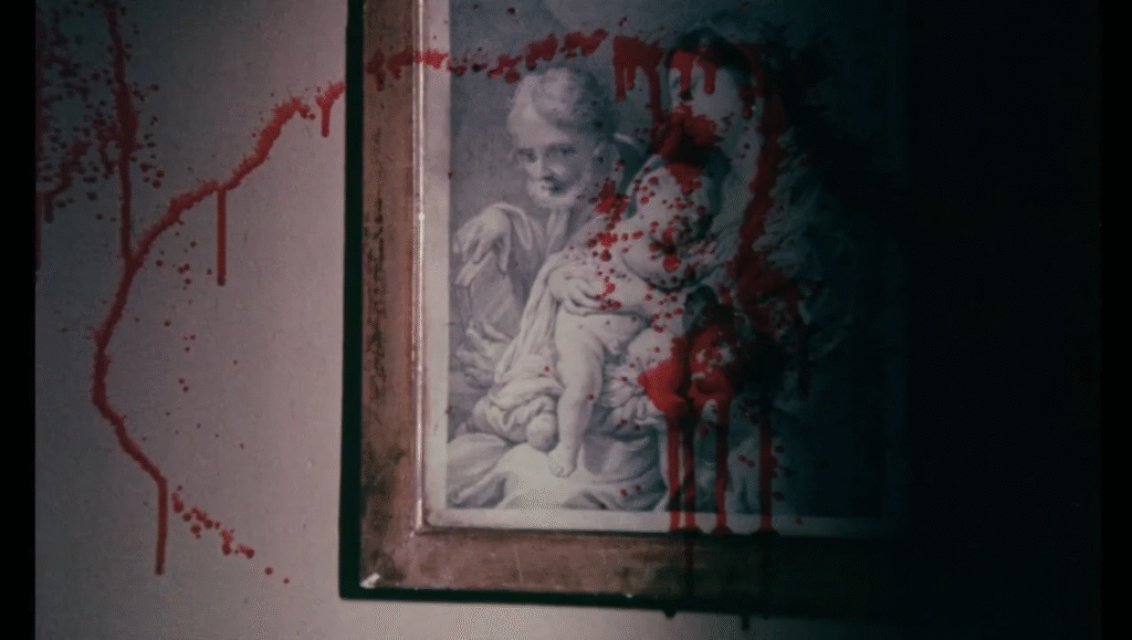 A framed painting hanging on a wall blood splattered across it.