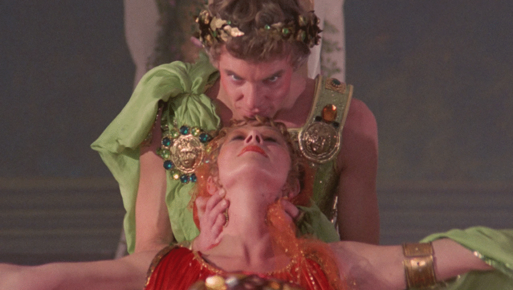 Malcolm McDowell as Caligula kissing a woman in red robes on the forehead.