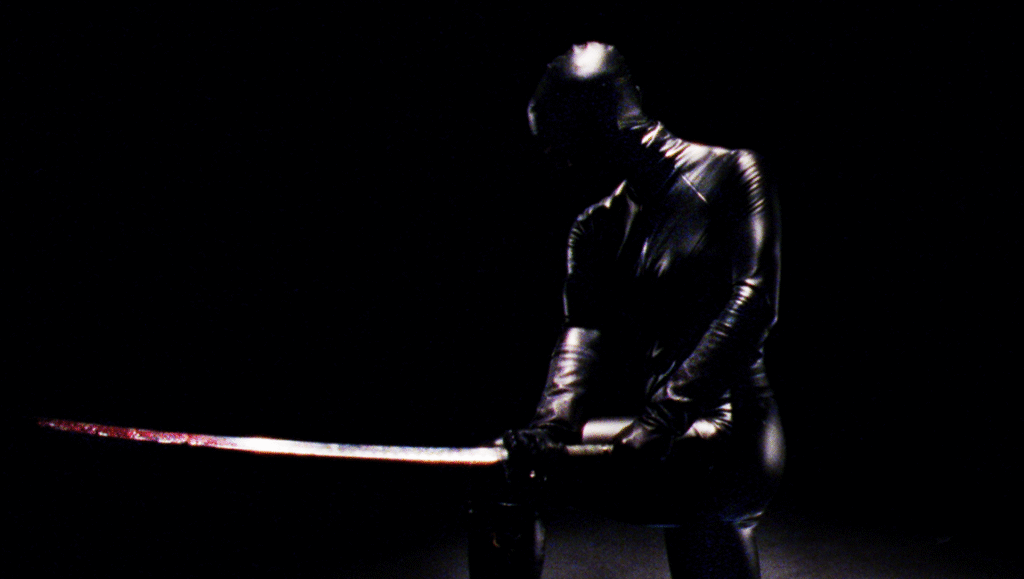 An image of a person in a black latex suit holding a sword.