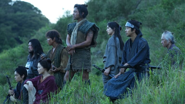 Japanese samurai warriors in period clothing stand in a field with swords. Historical drama.