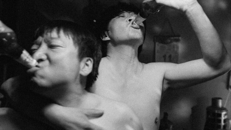 NYAFF 2025: Bel Ami still. Two shirtless men drink beer from bottles in a black and white film still. Queerpanorama.