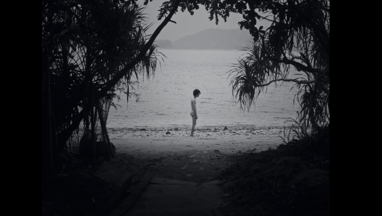Black and white still from Queerpanorama at NYAFF. Person stands on a beach.