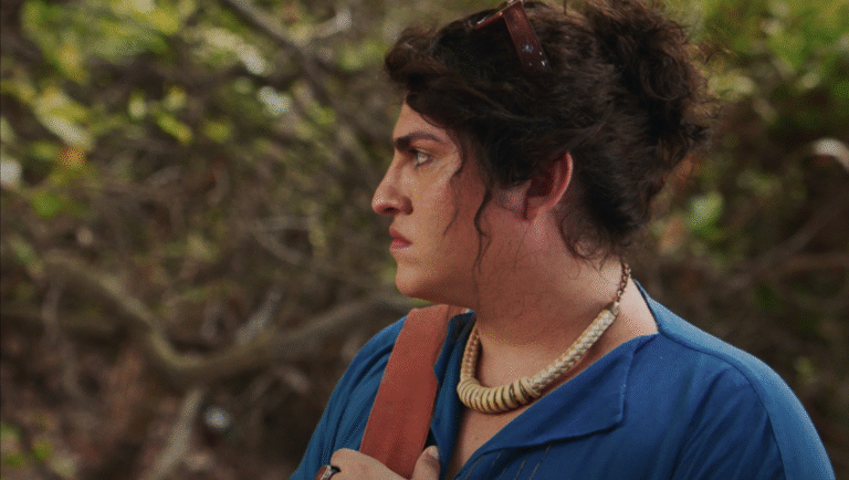 Film still from Death and Life Madalena at FIDMarseille 2025. Woman in blue shirt with necklace, looking left.