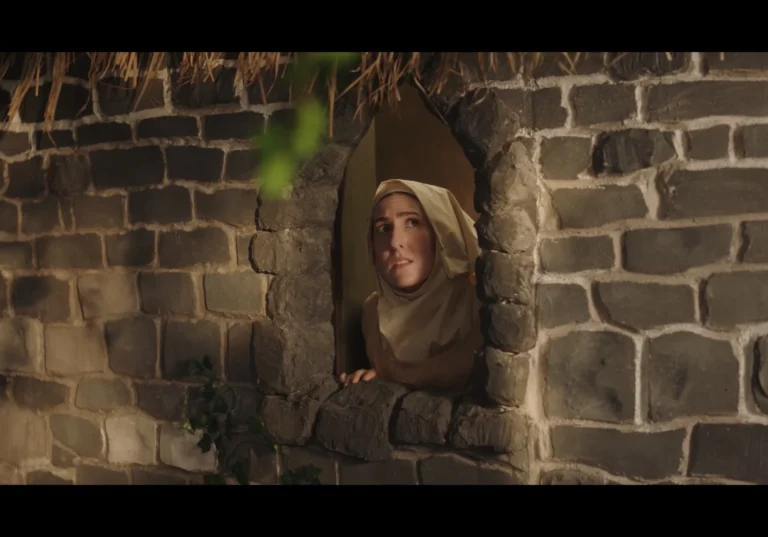 Film still from FIDMarseille 2025 Dispatch 1: Woman in headscarf looks out stone window. Revelations of Divine Love.