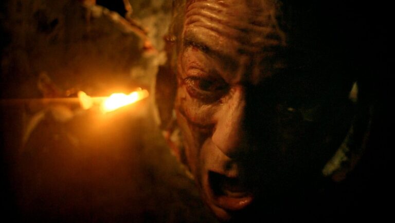 Horror movie scene. Close-up of a scary, screaming monster face in the dark with a bright light.