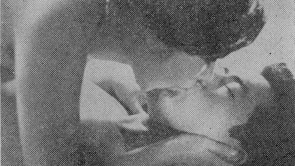 Grainy black and white photo of a person biting another person's nose.